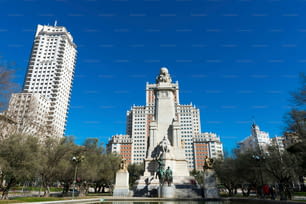 Wide angle view of Plaza de España and the surrounding historic buildings on a sunny winter morning, with the statue commemorating Cervantes in the foreground.