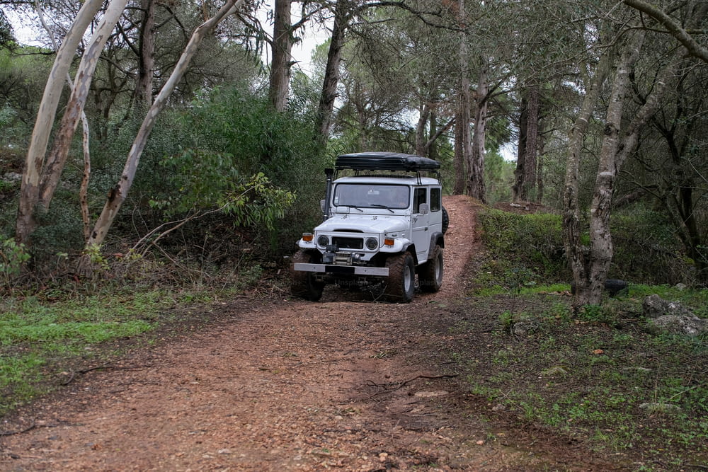 a jeep is parked on a dirt road in the woods