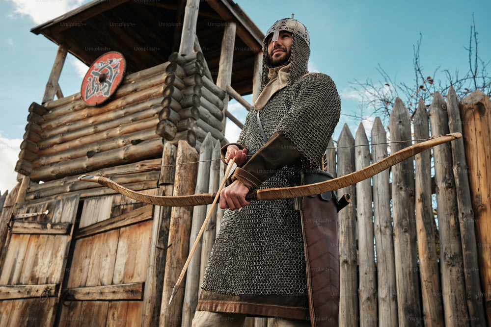 ein Mann in mittelalterlicher Kleidung, der Pfeil und Bogen in der Hand hält