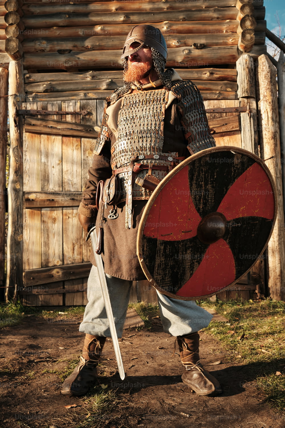 Ein Mann in mittelalterlicher Kleidung, der einen Schild und ein Schwert in der Hand hält