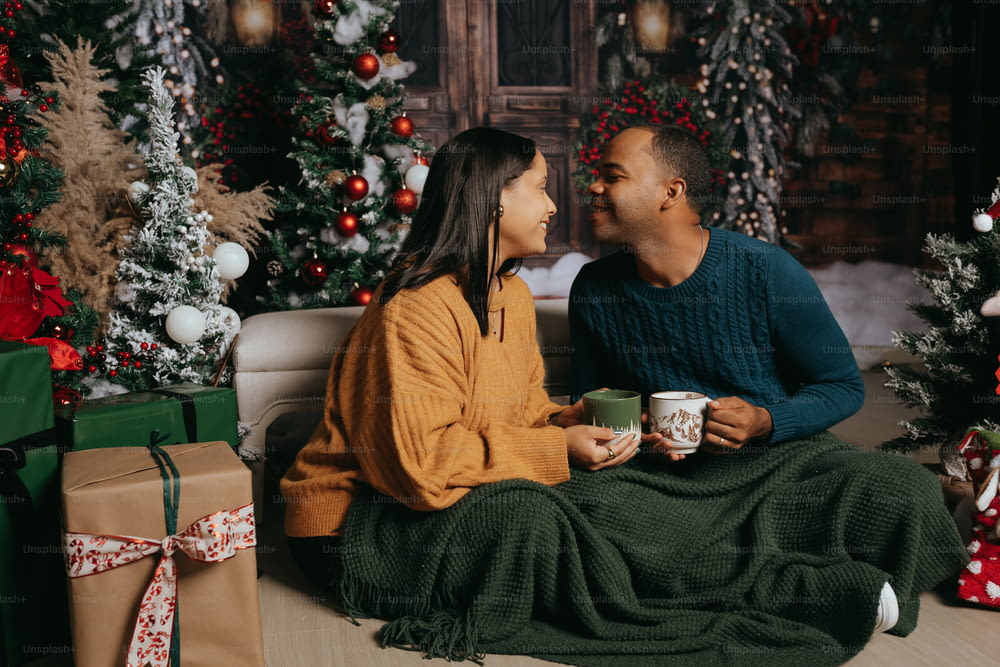 a man and woman sitting on a couch next to a christmas tree