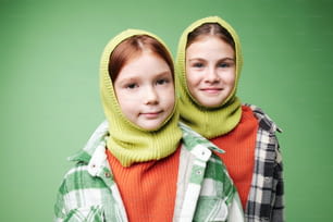 two young girls wearing knitted hoods and scarves