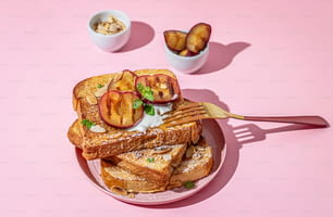 a pink plate topped with french toast and sliced peaches