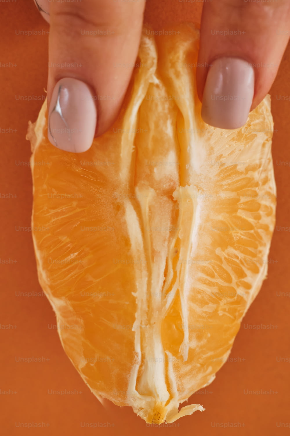 오렌지 반쪽을 들고 있는 여자의 손