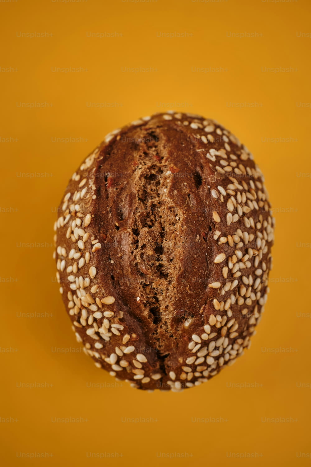 a loaf of bread with sesame seeds on a yellow background