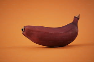 eine rote Banane, die auf einer orangefarbenen Oberfläche sitzt
