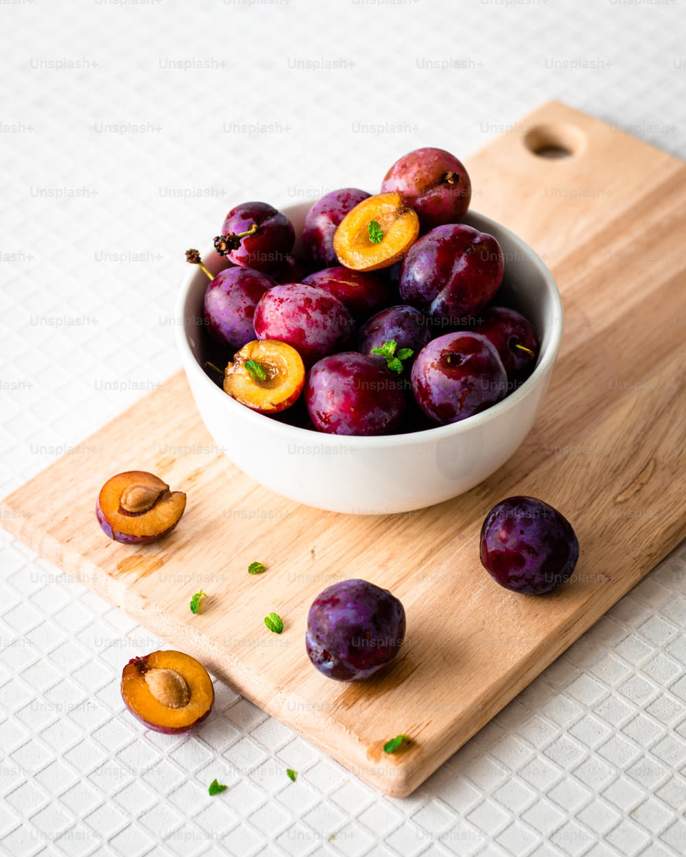 a bowl of plums on a cutting board