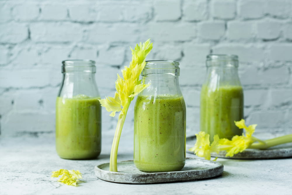 a green smoothie in a glass jar with a yellow flower sticking out of it