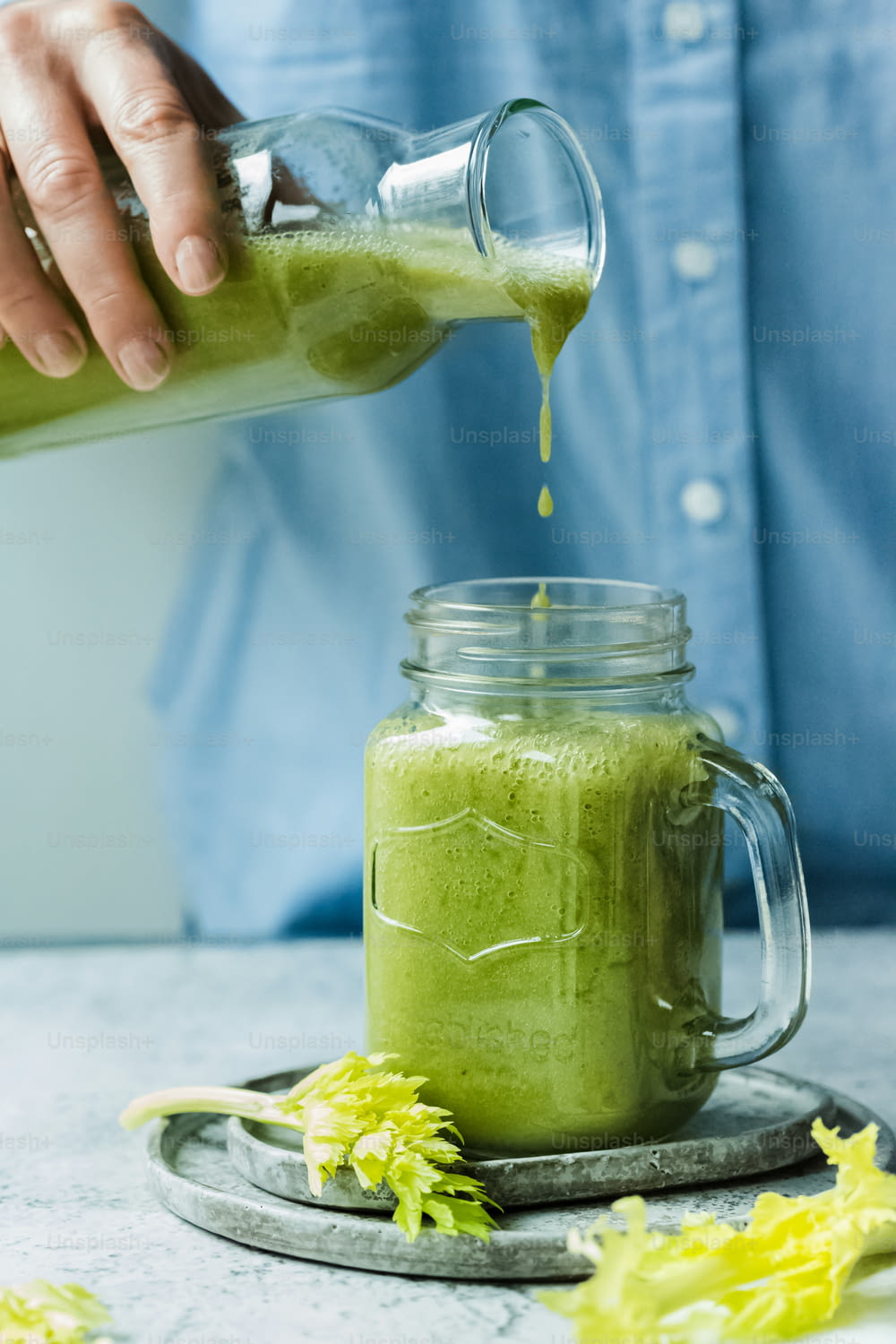 a person pouring a green smoothie into a mason jar