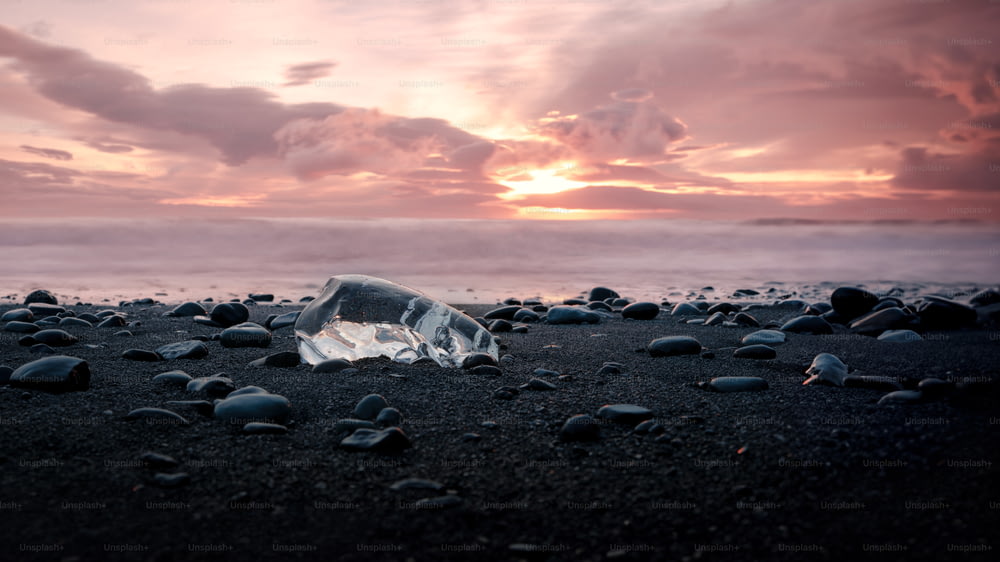 uma garrafa de vidro quebrada sentada em cima de uma praia de areia