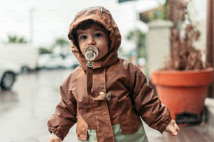 a small child wearing a rain coat and a pacifier