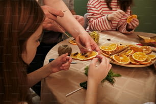 a group of people sitting around a table cutting orange slices
