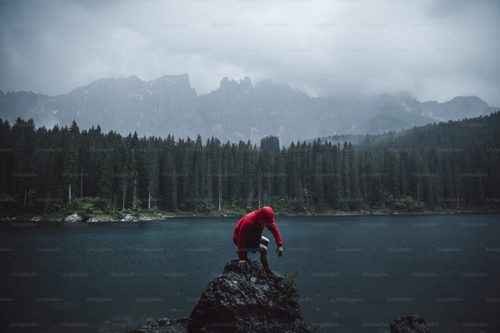a person standing on a rock in front of a lake