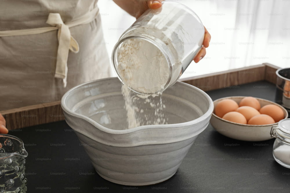 a person pouring water into a bowl of eggs