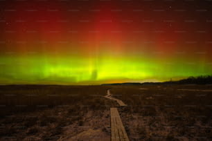 Un sentiero che porta a un'aurora verde e rossa