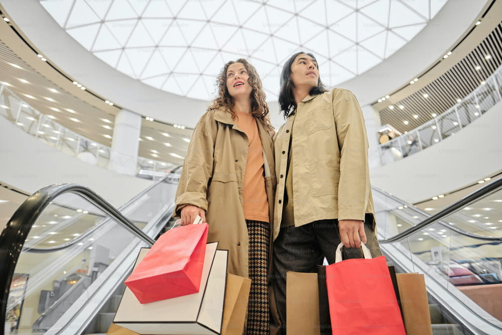 a couple of women standing next to each other holding shopping bags