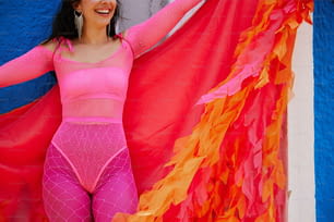 a woman in a pink bodysuit holding a red and orange flag