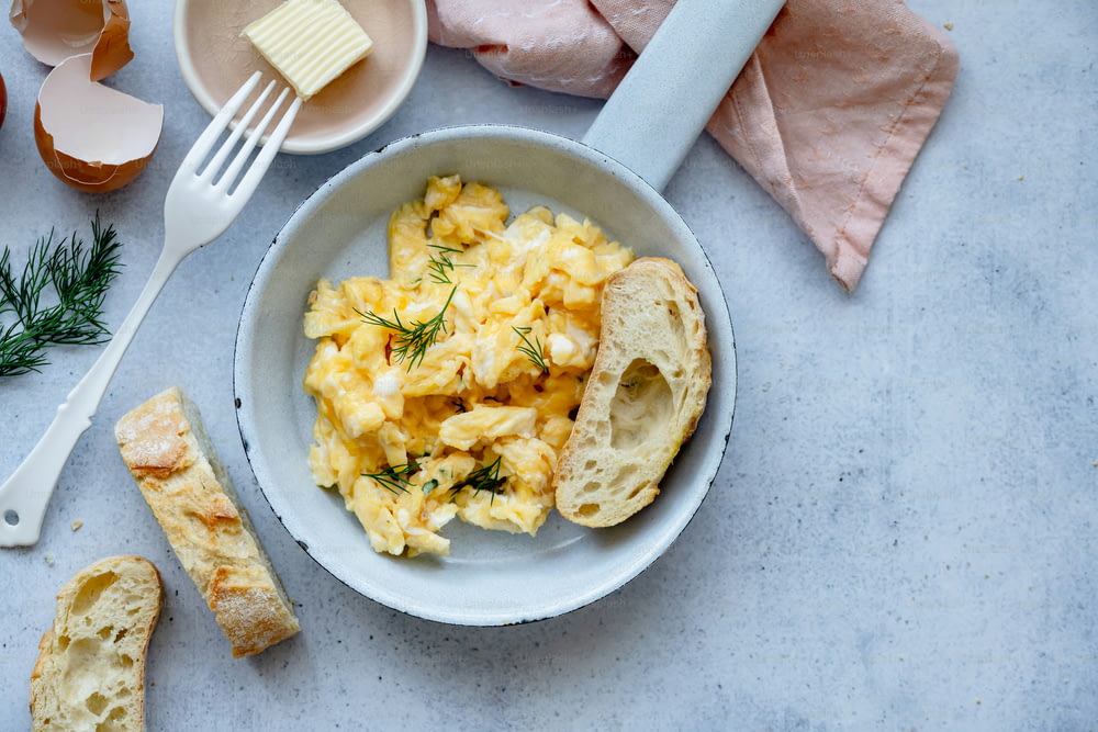 a bowl of scrambled eggs with bread and butter