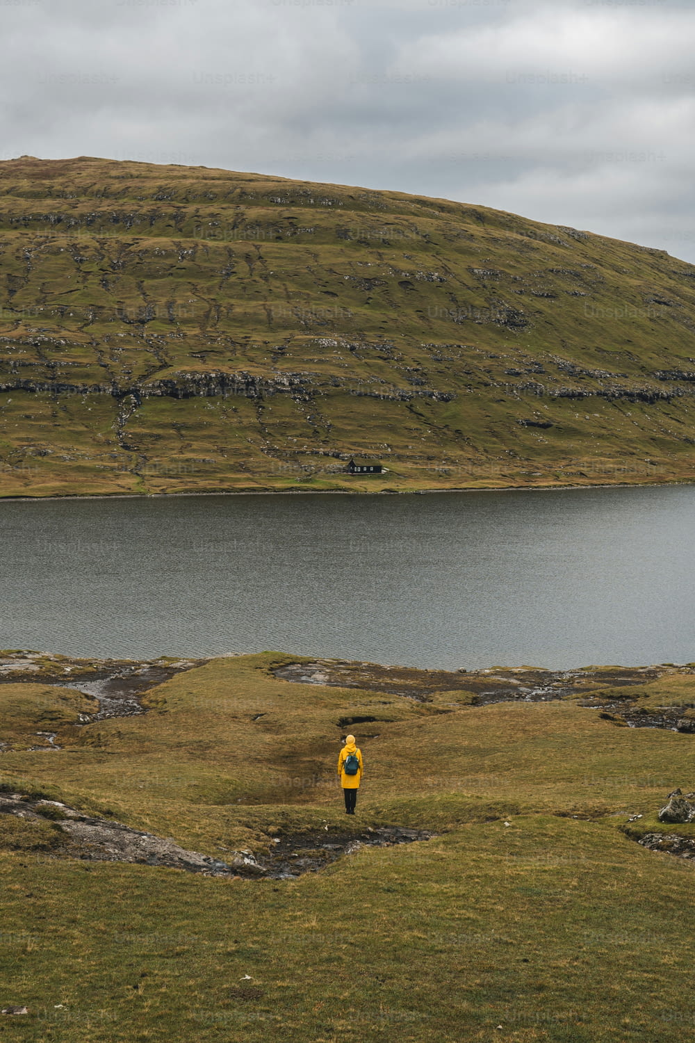 una persona in una giacca gialla in piedi davanti a uno specchio d'acqua