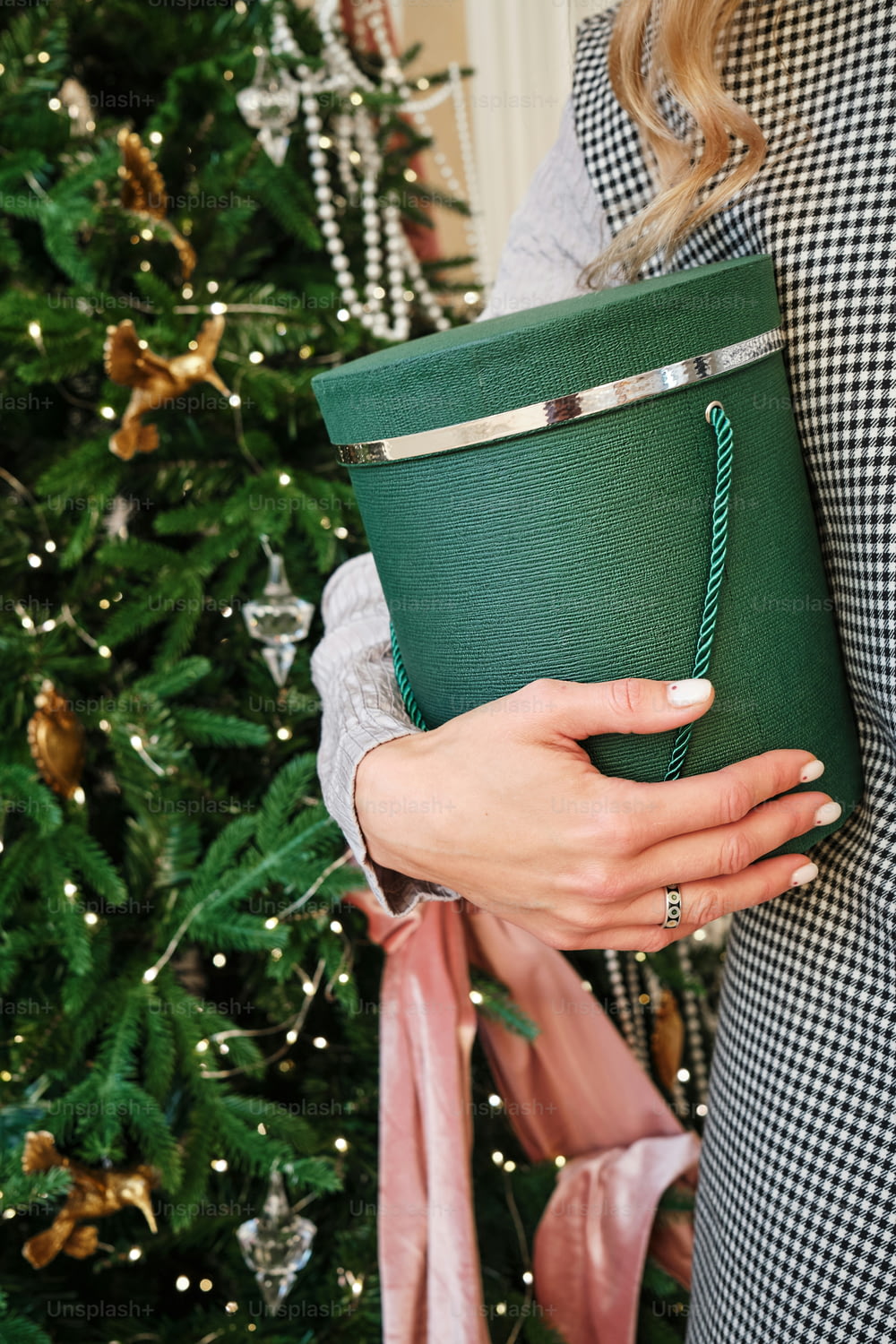 a woman holding a green cup in front of a christmas tree