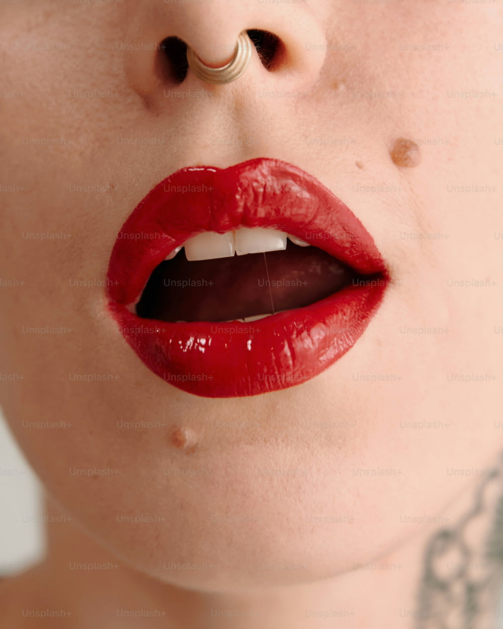 eine Frau mit rotem Lippenstift und Piercings auf den Lippen