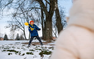 a young boy playing with a frisbee in the snow