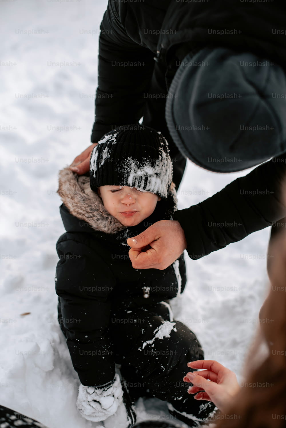 a small child sitting in the snow with a hat on