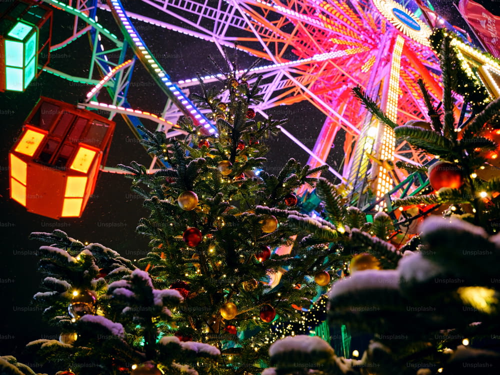 a brightly lit christmas tree in front of a ferris wheel