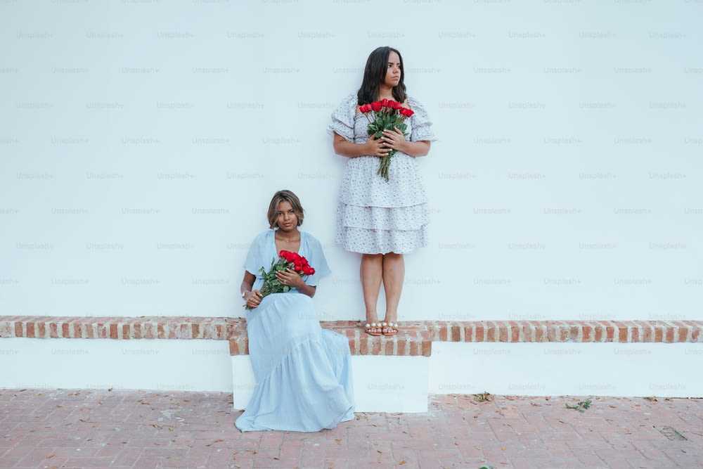 two women standing next to each other holding roses