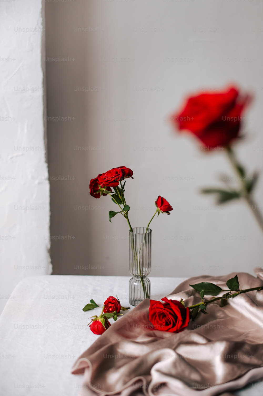 three red roses in a vase on a table