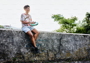 a person sitting on a wall with a frisbee
