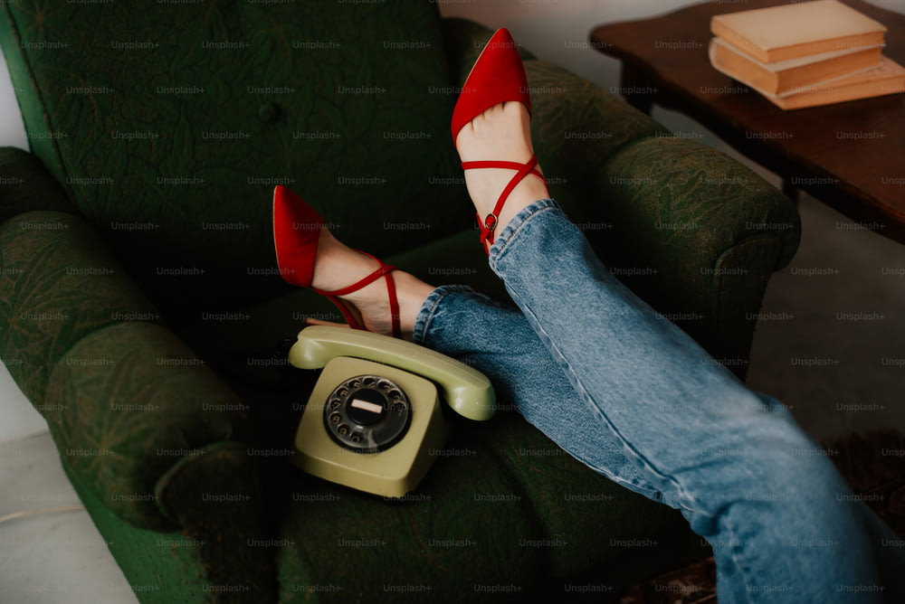 a woman's legs resting on a green chair while holding a phone