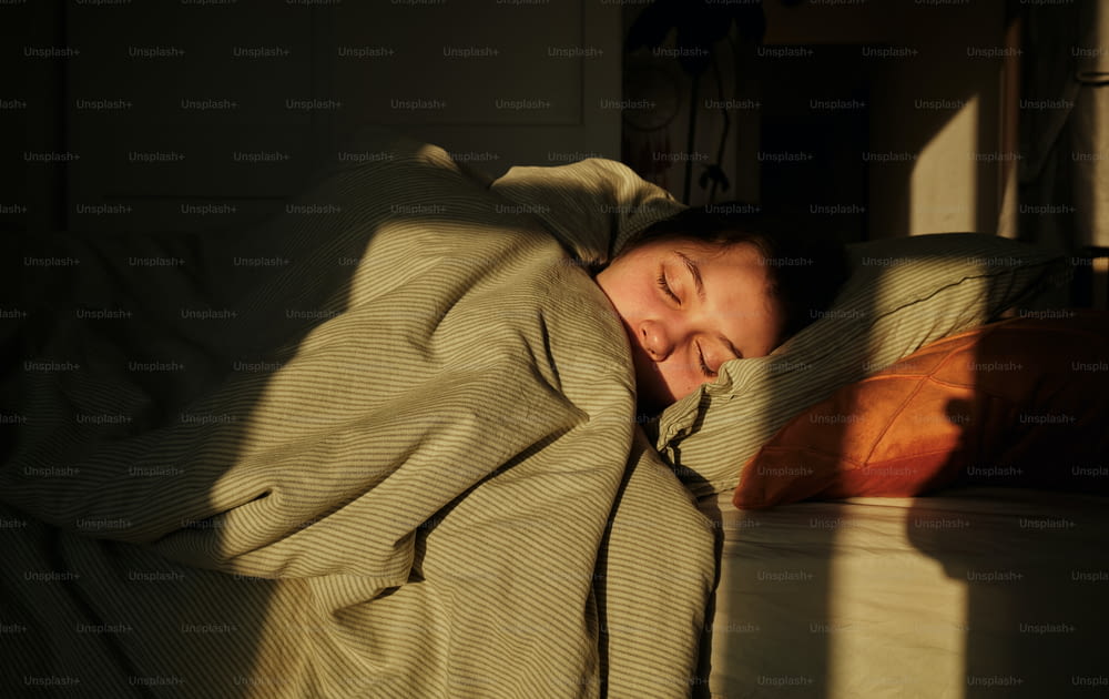 a woman is sleeping in a bed with a blanket