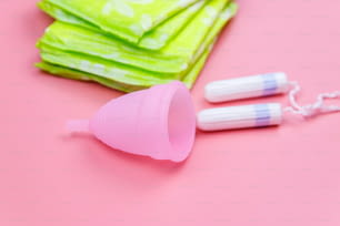 ピンクの背景に生理用ナプキン、タンポン、月経カップ。重要な日、月経、女性の衛生の概念