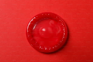 Preservativo vermelho único no fundo vermelho, vista superior