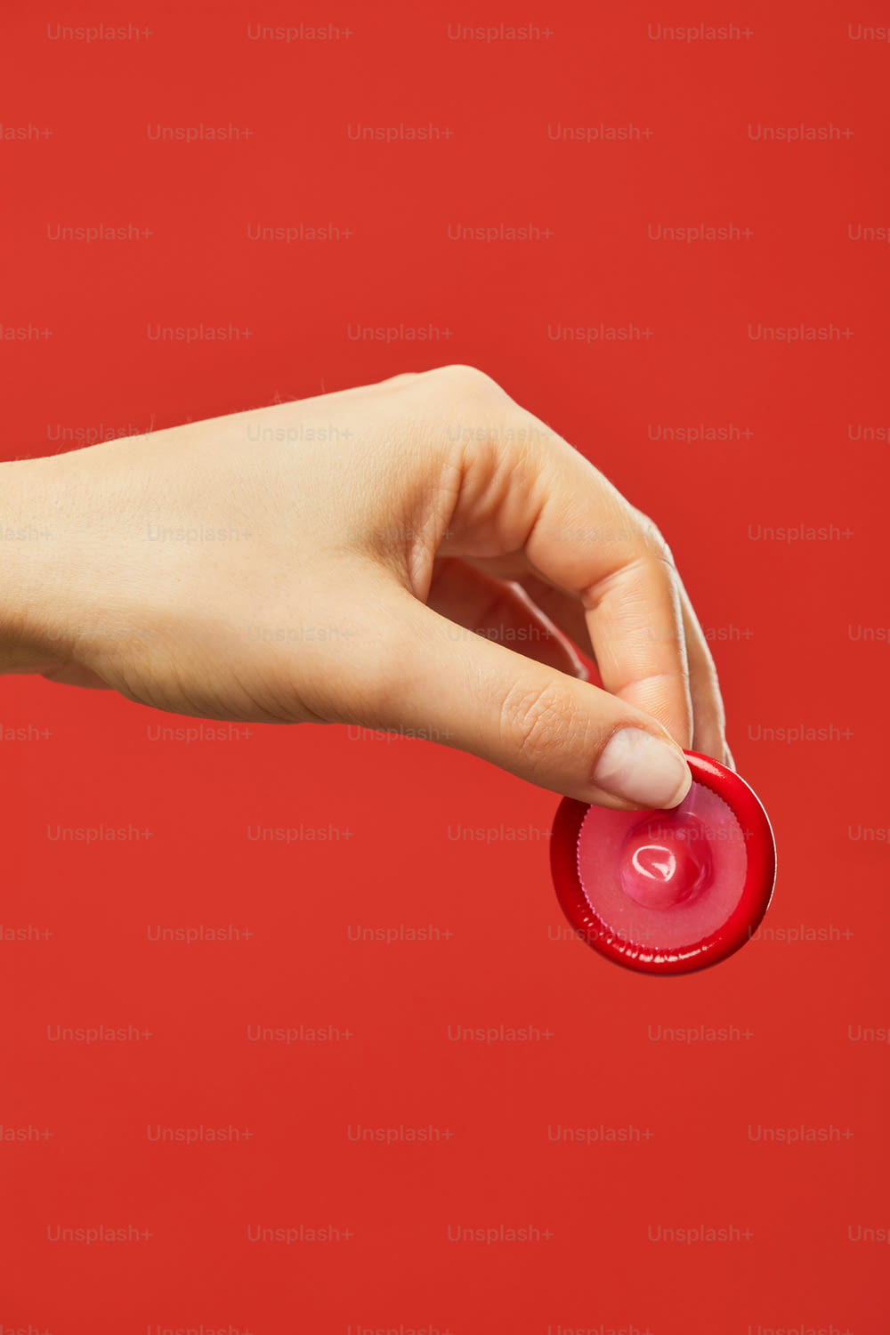 Vibrant closeup of female hand holding condom against red background safe sex and protection concept