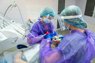 a patient with an ingrown tooth problem lies on an operating chair where he is operated on by a dentist and his assistants. The concept of surgery at the dentist