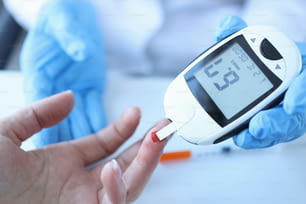 Médico midiendo la glucosa en sangre de los pacientes con un primer plano del glucómetro. Diagnóstico del concepto de diabetes
