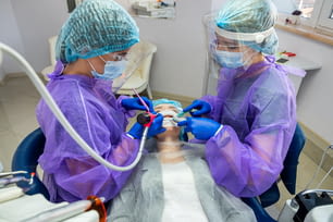 Um dentista competente e seu assistente realizam a operação no consultório para instalar um implante dentário. Conceito odontológico
