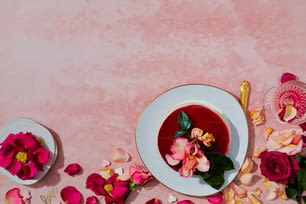 a bowl of soup with pink flowers on a pink background