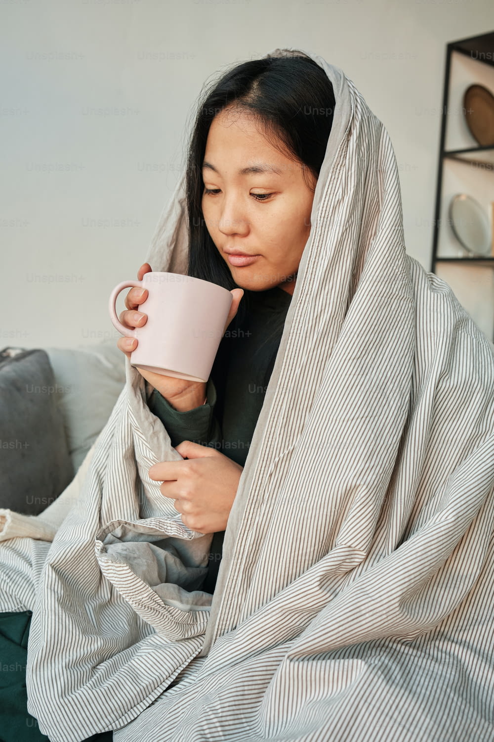 a woman wrapped in a blanket holding a cup