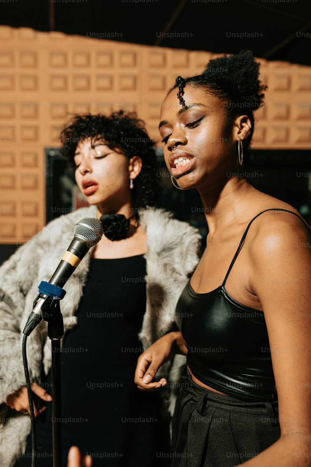 two women standing next to each other in front of a microphone