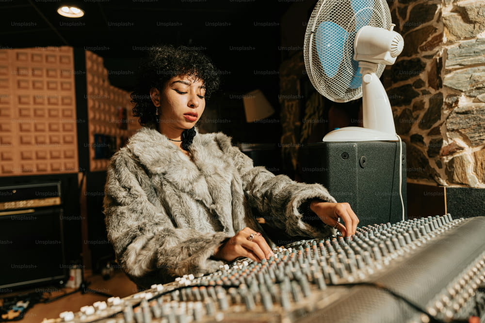a woman in a fur coat sitting at a mixing desk