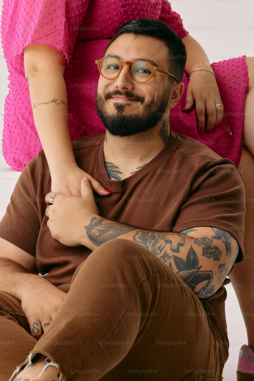 a man with a tattooed arm sitting on a woman's lap