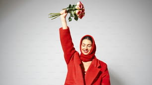uma mulher em um casaco vermelho segurando um buquê de flores
