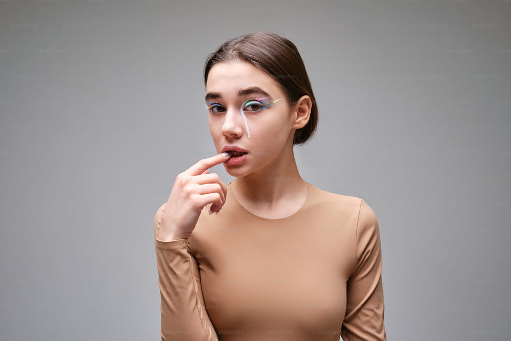 a woman in a tan top is holding her finger to her lips