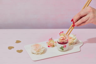 a person holding chopsticks over a cup with flowers on it