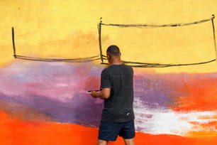 a man standing in front of a wall with a cell phone in his hand