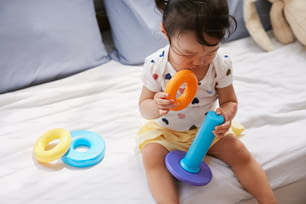uma menina sentada em uma cama brincando com um brinquedo