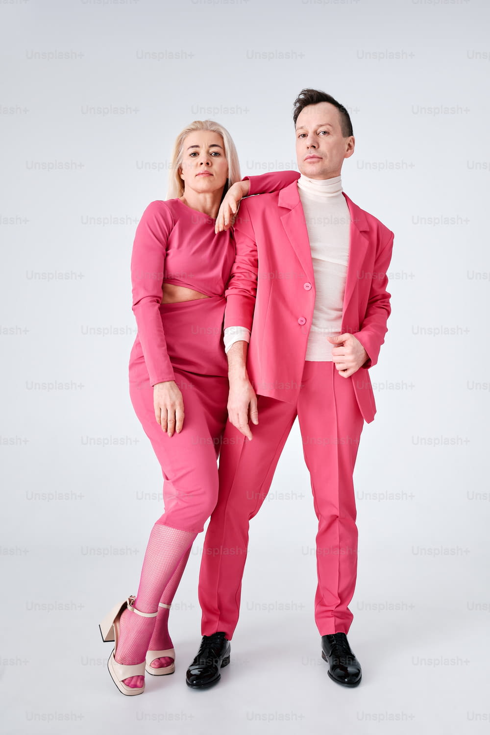 um homem de terno rosa e uma mulher de top branco